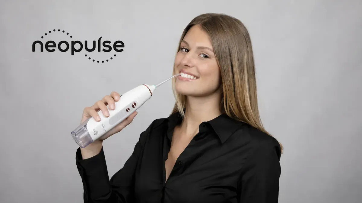 Une utilisatrice souriante avec un hydropulseur Neopulse, logo de la marque à côté