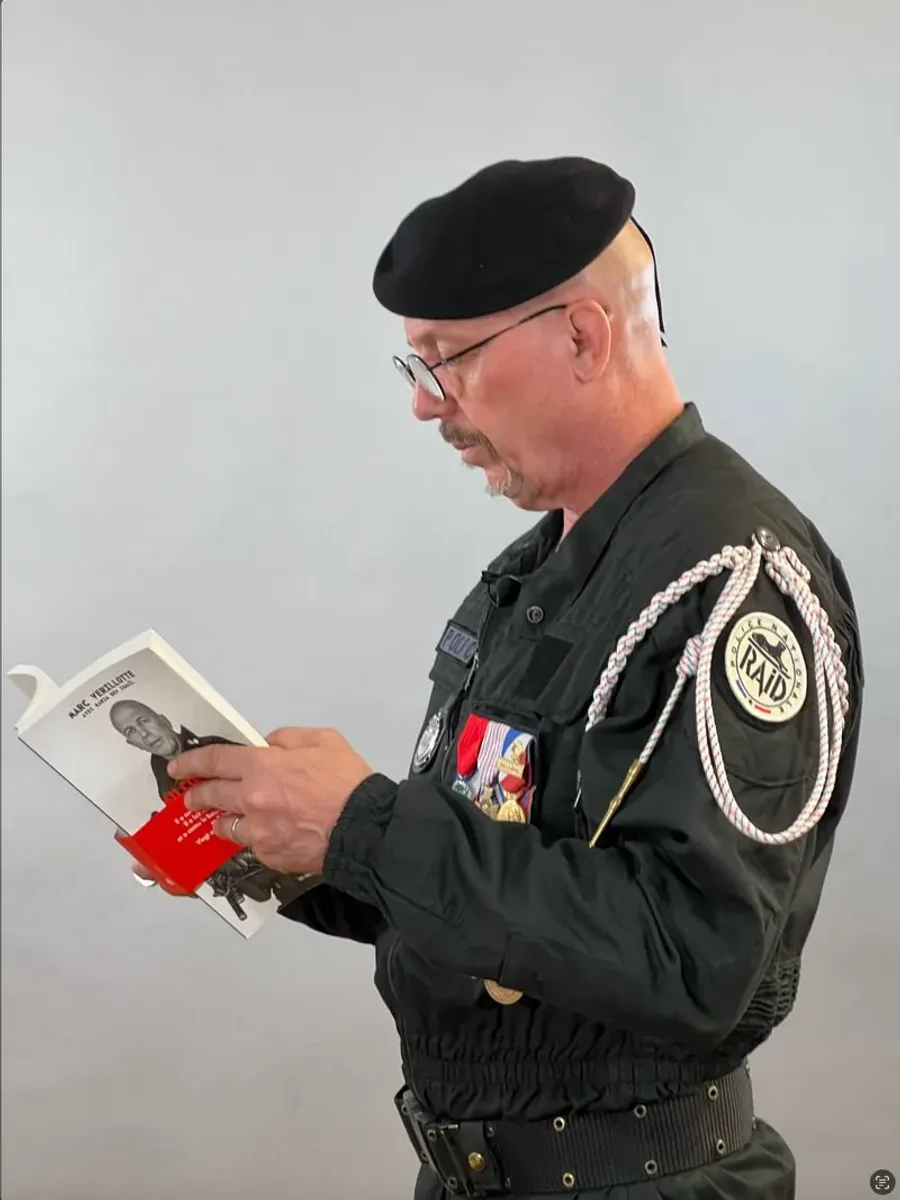 Captation d’un intervenant en uniforme lisant un ouvrage face caméra